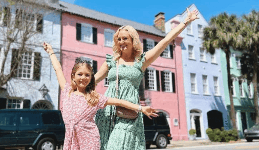 Mother and daughter posing happily in front of the colorful houses of Rainbow Row in Charleston