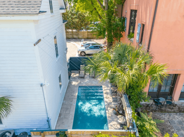Aerial view of the 257 Rutledge guest pool between historic buildings, with lounge chairs and a palm tree.