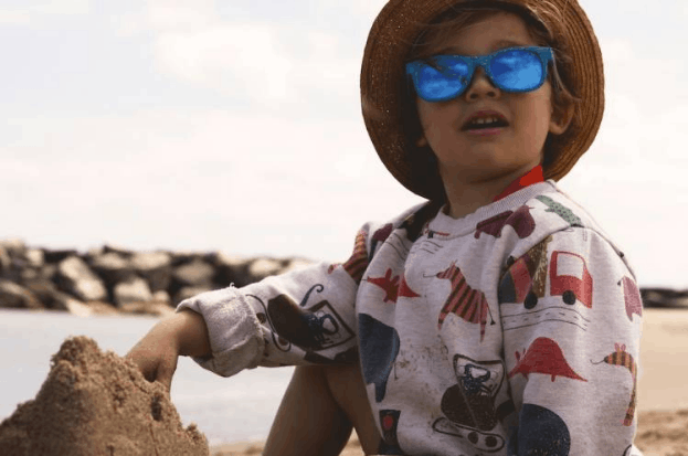 Child building a sandcastle on the beach during a family hotel vacation.