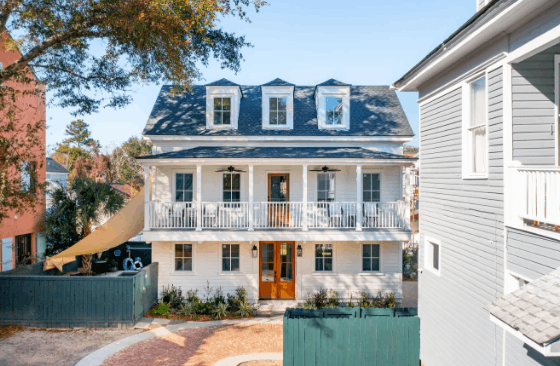 Exterior view of 257 Rutledge Inns, featuring a beautifully restored historic white house with a multi-level porch, wooden double doors, and dormer windows.