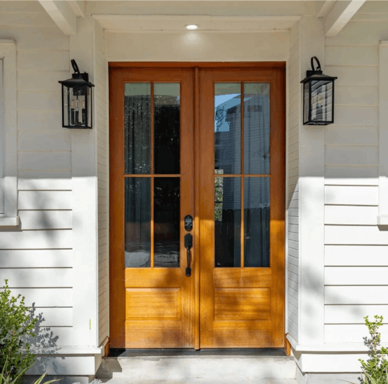 Main entrance of 257 Rutledge Inns featuring elegant double wooden French doors with glass panes and modern black wall lanterns.