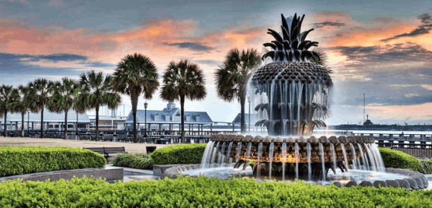 The historic Pineapple Fountain lit up at sunset in Waterfront Park, a top
  attraction for guests visiting Charleston, South Carolina.