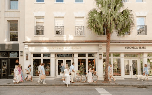 A bustling sidewalk in front of Clayton & Crume and Veronica Beard shops on historic King Street in Charleston, South Carolina.