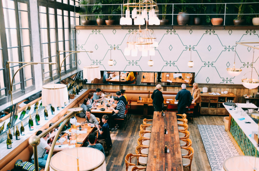 Spacious restaurant with stylish interior design, featuring wooden tables and a group of diners enjoying a meal