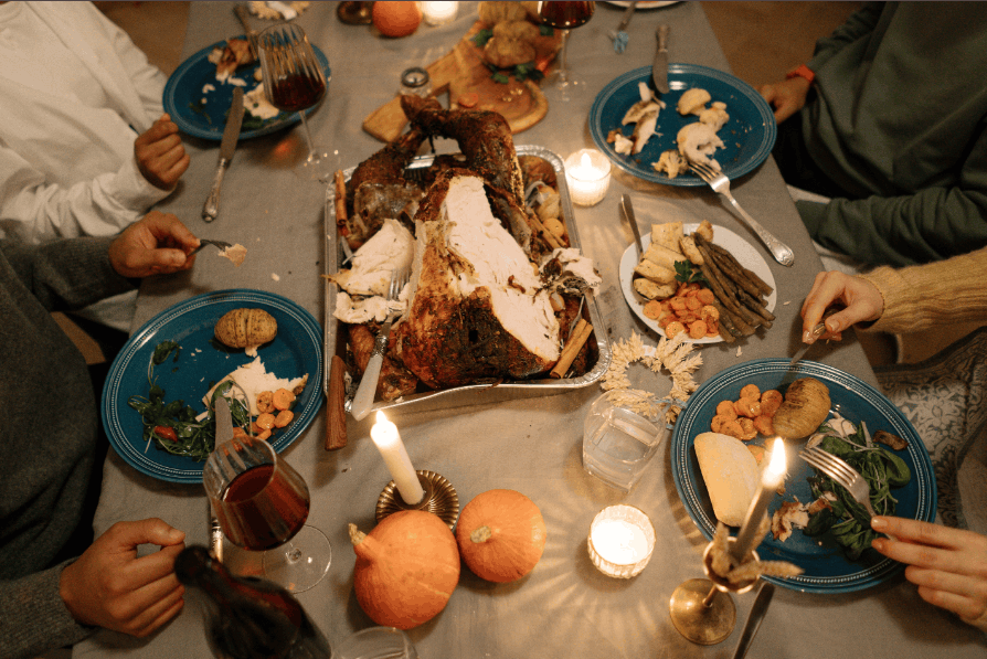 Top view of a cozy holiday dinner with a roasted turkey centerpiece and festive table setting